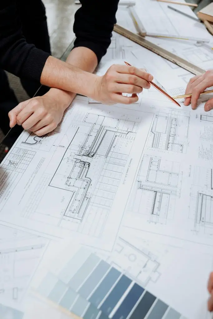 Accueil 1 Architects discussing detailed blueprints and schematics at a table.